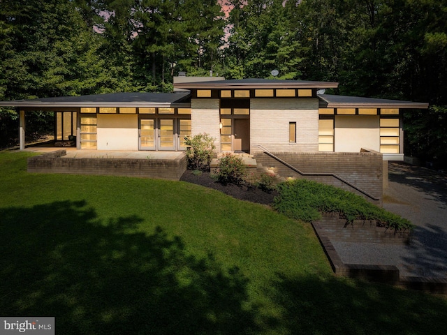 view of front of house featuring a patio, brick siding, a chimney, and a front yard