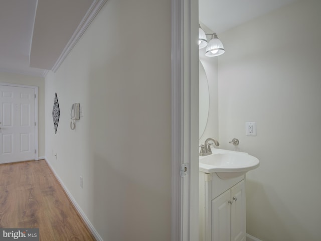 bathroom with crown molding, vanity, baseboards, and wood finished floors