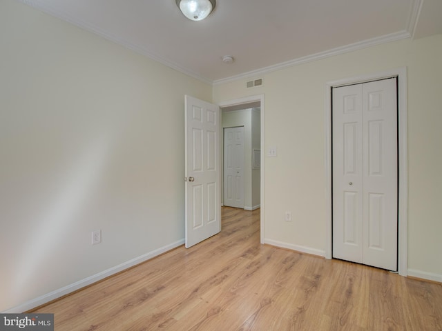 unfurnished bedroom with light wood-style flooring, visible vents, baseboards, and ornamental molding