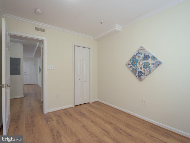 unfurnished bedroom featuring electric panel, baseboards, visible vents, light wood-style flooring, and crown molding