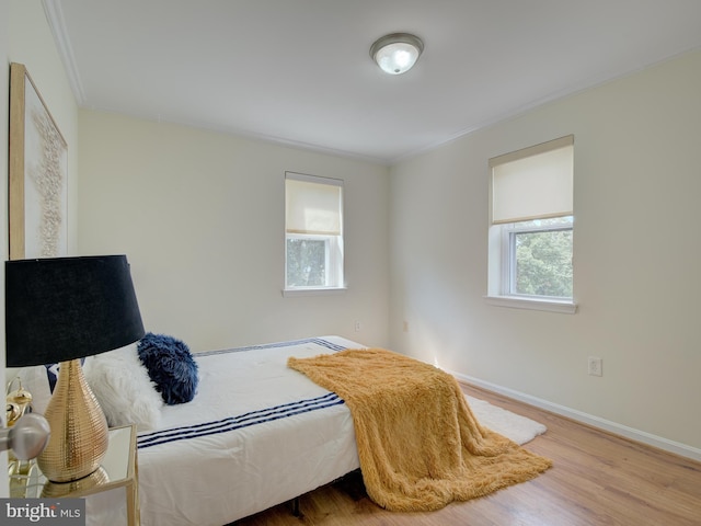 bedroom featuring baseboards, wood finished floors, and ornamental molding