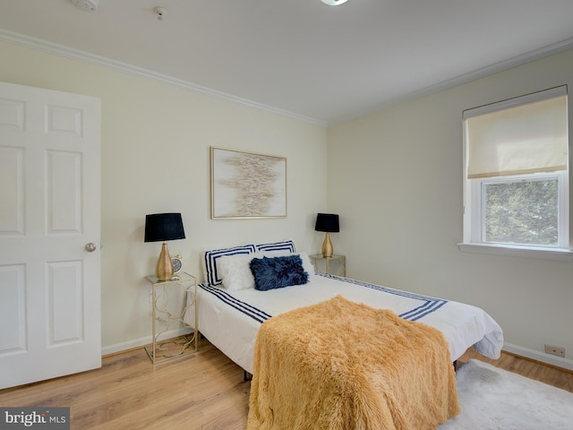 bedroom featuring baseboards, crown molding, and light wood finished floors