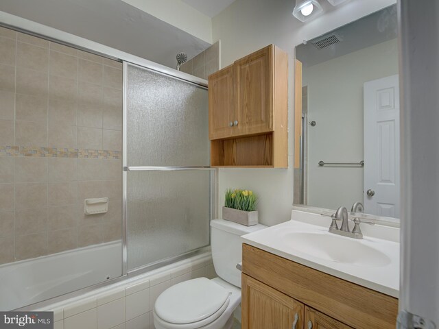 full bath with visible vents, shower / bath combination with glass door, vanity, and toilet