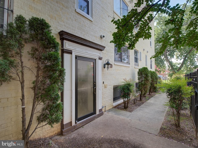 doorway to property with brick siding and fence