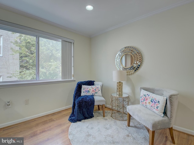 living area with crown molding and light hardwood / wood-style flooring