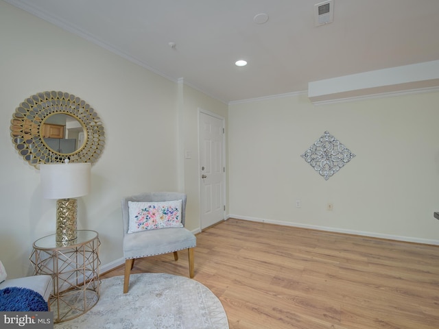 living area featuring recessed lighting, visible vents, ornamental molding, light wood-type flooring, and baseboards