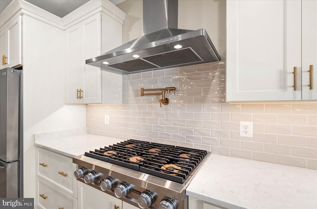 kitchen with appliances with stainless steel finishes, white cabinetry, and wall chimney exhaust hood