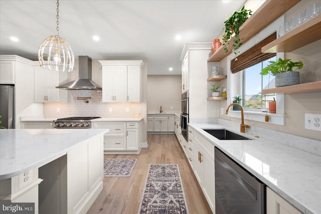 kitchen with wall chimney exhaust hood, light hardwood / wood-style flooring, stainless steel appliances, sink, and light stone counters