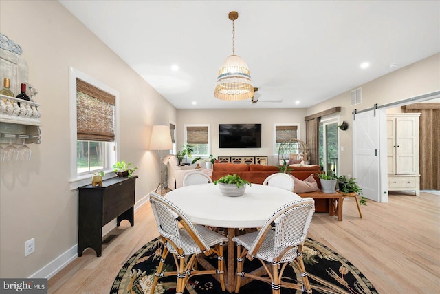 dining space with a barn door, an inviting chandelier, and light hardwood / wood-style floors