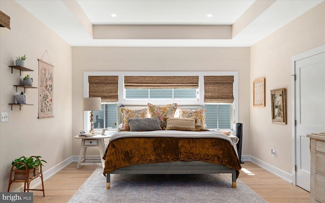 bedroom featuring a raised ceiling and light wood-type flooring