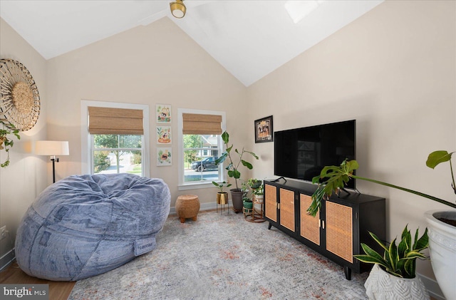 living area featuring vaulted ceiling, wood finished floors, and baseboards