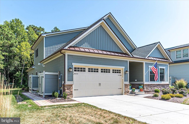 craftsman-style house with an attached garage, a standing seam roof, stone siding, and concrete driveway