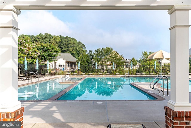 pool with a patio area and fence