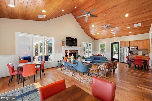 living room with high vaulted ceiling, a healthy amount of sunlight, ceiling fan, and a brick fireplace