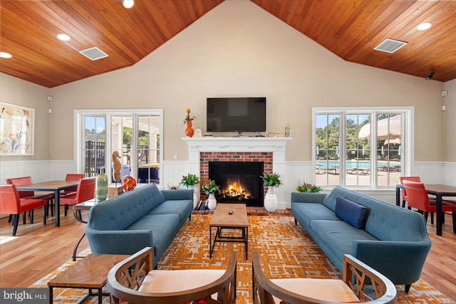 living room featuring hardwood / wood-style floors, high vaulted ceiling, a fireplace, and wooden ceiling