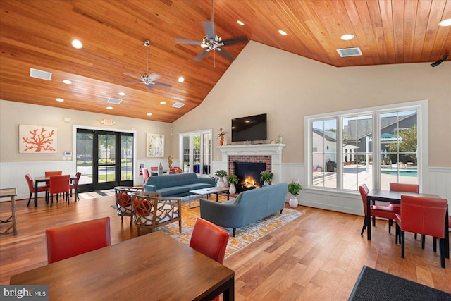 dining area with a fireplace, wood ceiling, light hardwood / wood-style floors, ceiling fan, and high vaulted ceiling