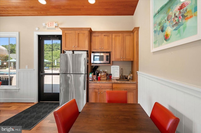 kitchen with wooden ceiling, stone countertops, light hardwood / wood-style flooring, stainless steel appliances, and sink