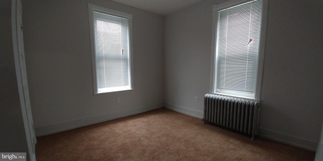 carpeted spare room featuring radiator