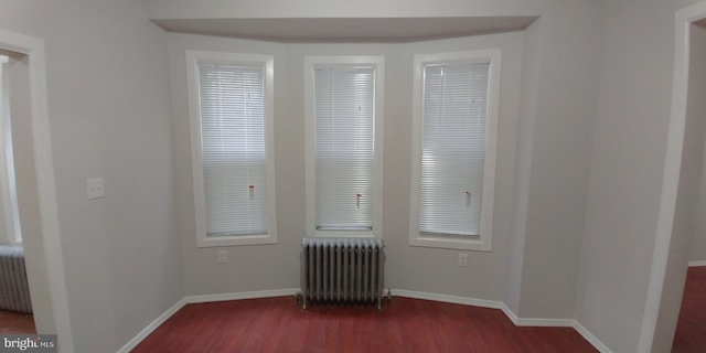 unfurnished room with radiator heating unit and dark wood-type flooring