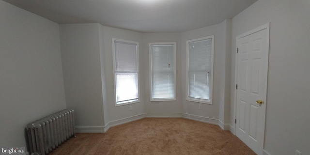 unfurnished room with light carpet and radiator