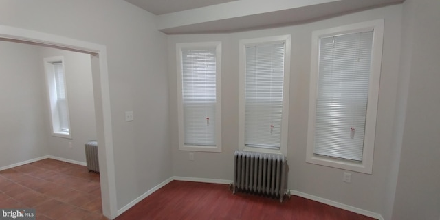 unfurnished room with dark wood-type flooring and radiator heating unit