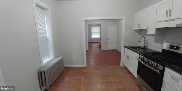 kitchen featuring stainless steel gas stove, radiator, and white cabinets