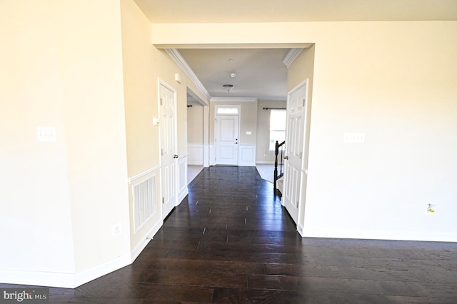 hall featuring dark wood-style floors, baseboards, visible vents, and crown molding