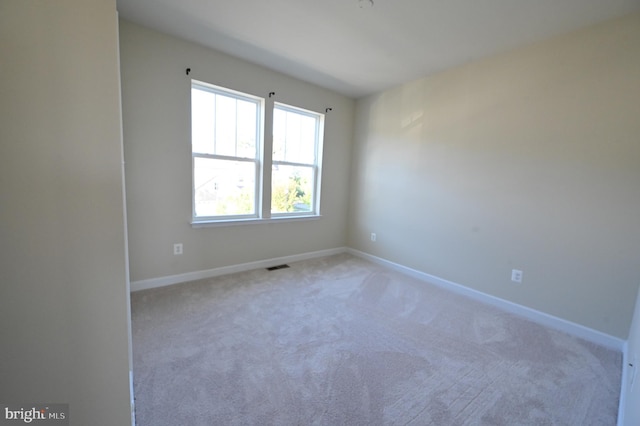 empty room with light colored carpet, visible vents, and baseboards