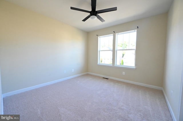 empty room featuring a ceiling fan, visible vents, light carpet, and baseboards