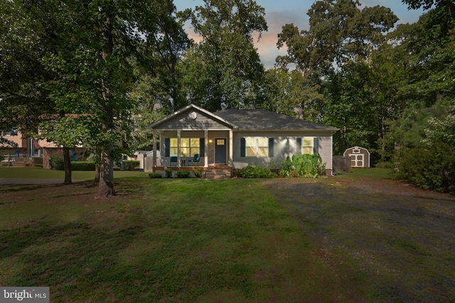 view of front of property with covered porch, a shed, and a yard