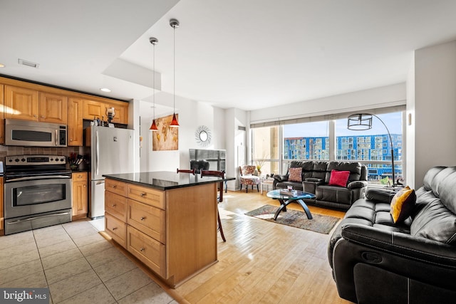 kitchen featuring appliances with stainless steel finishes, light hardwood / wood-style flooring, a healthy amount of sunlight, and a breakfast bar area