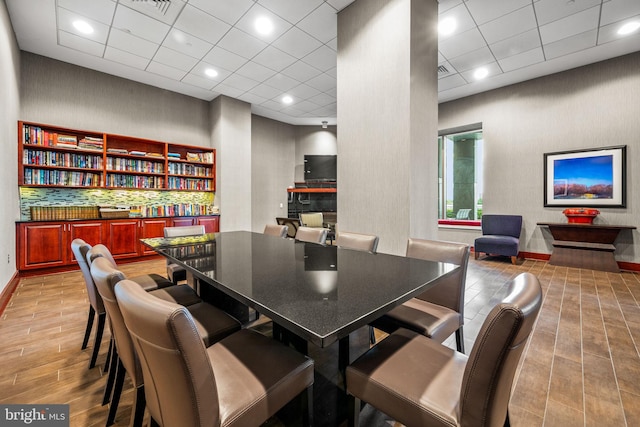 dining area featuring light wood finished floors, baseboards, and a drop ceiling