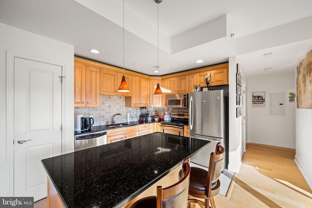 kitchen with dark stone counters, light wood-type flooring, appliances with stainless steel finishes, tasteful backsplash, and a kitchen island