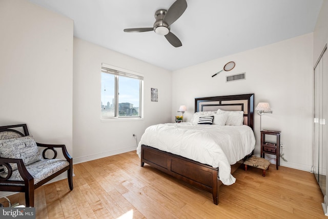 bedroom with ceiling fan, light wood finished floors, visible vents, and baseboards