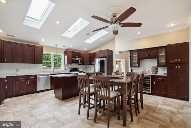 kitchen with a kitchen island, decorative light fixtures, vaulted ceiling, decorative backsplash, and appliances with stainless steel finishes