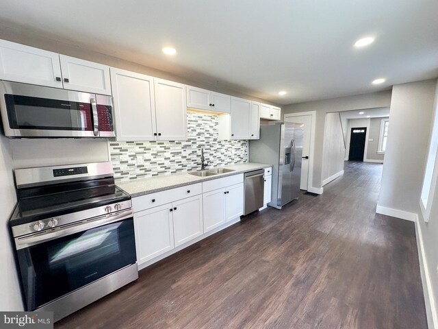 kitchen featuring backsplash, dark wood-type flooring, white cabinets, sink, and stainless steel appliances