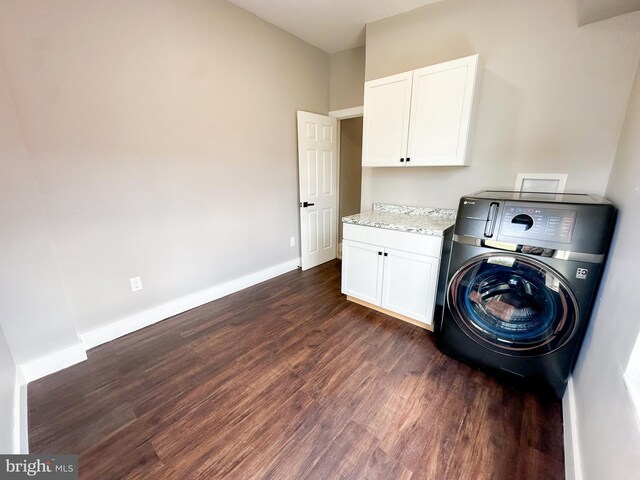 clothes washing area with washer / dryer, dark wood-type flooring, and cabinets