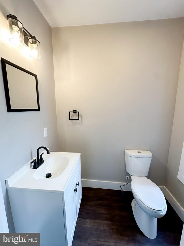 bathroom featuring wood-type flooring, toilet, and vanity