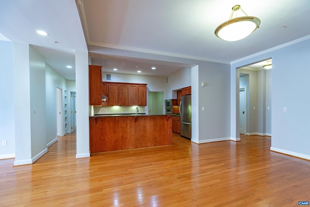 kitchen with light hardwood / wood-style floors, a raised ceiling, kitchen peninsula, and a kitchen bar