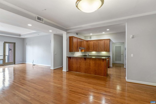 kitchen featuring open floor plan, light wood-style floors, baseboards, a peninsula, and visible vents