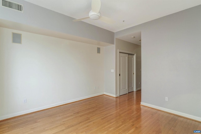 spare room with light wood-type flooring, baseboards, a ceiling fan, and visible vents