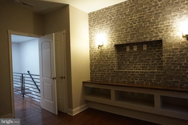 hall featuring dark hardwood / wood-style flooring and brick wall