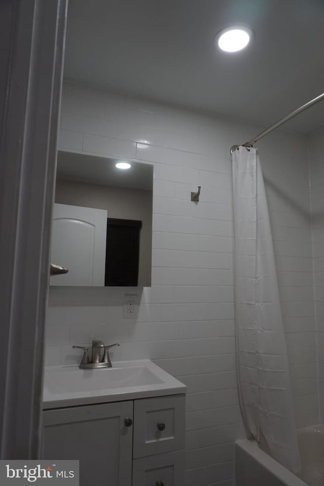 bathroom featuring tile walls, shower / bath combination with curtain, tasteful backsplash, and vanity