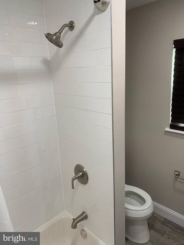 bathroom featuring tiled shower / bath, toilet, and hardwood / wood-style floors