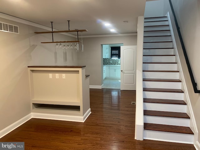 interior space featuring crown molding, dark wood-type flooring, and backsplash