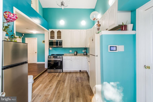 kitchen with white cabinets, stainless steel appliances, and light wood-type flooring