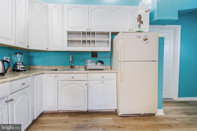 kitchen with light hardwood / wood-style flooring, white cabinetry, sink, and white refrigerator