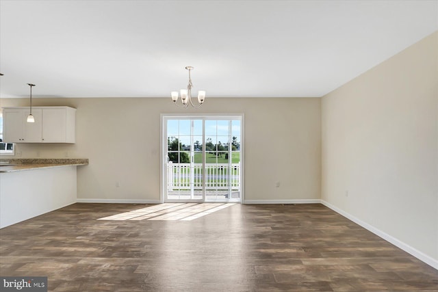 unfurnished dining area with an inviting chandelier, baseboards, and dark wood-type flooring