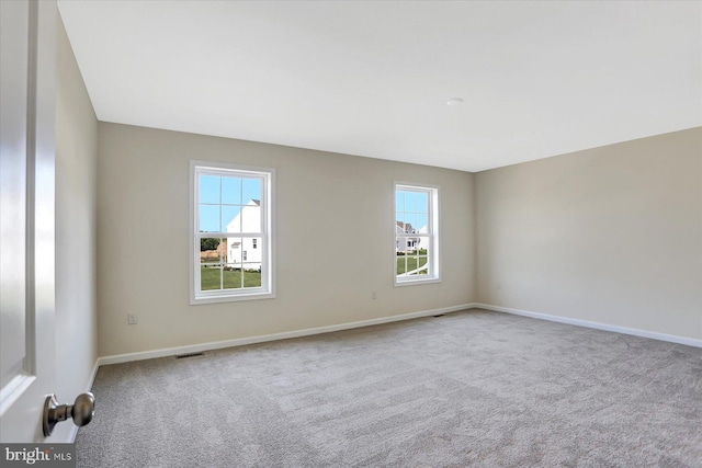 spare room with light carpet, plenty of natural light, and visible vents