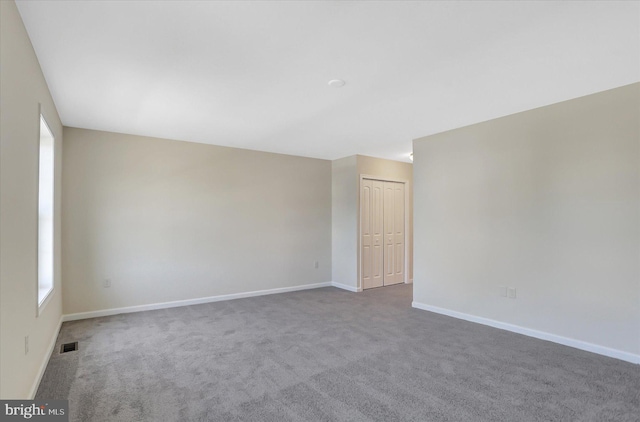 empty room featuring carpet flooring, visible vents, and baseboards